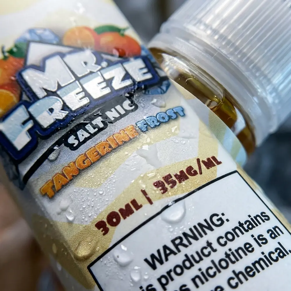 Detalhe extremo do rotulo e bico da garrafa Mr. Freeze Salt Tangerine Frost com gotas e textura de verniz - Vapor Gringo
