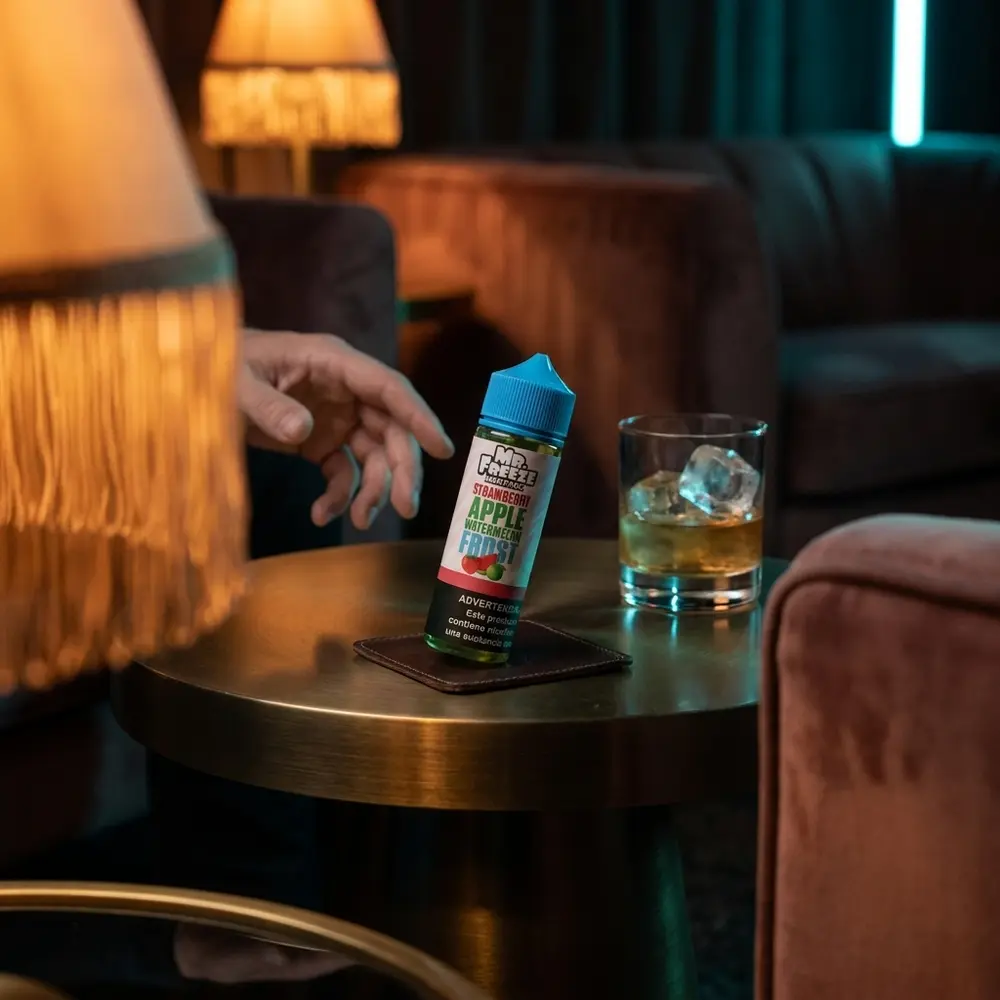 Frasco Mr. Freeze Strawberry Apple Watermelon Frost em lounge de luxo com luzes quentes e neon, copo com gelo ao lado - Vapor Gringo