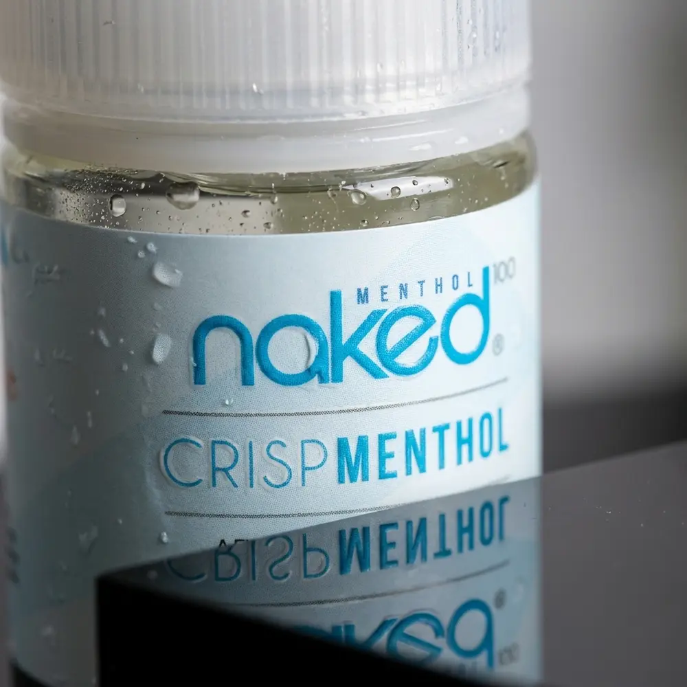 Close-up do rótulo Naked 100 Crisp Menthol com gotas de condensação no bico e reflexos metálicos - Vapor Gringo