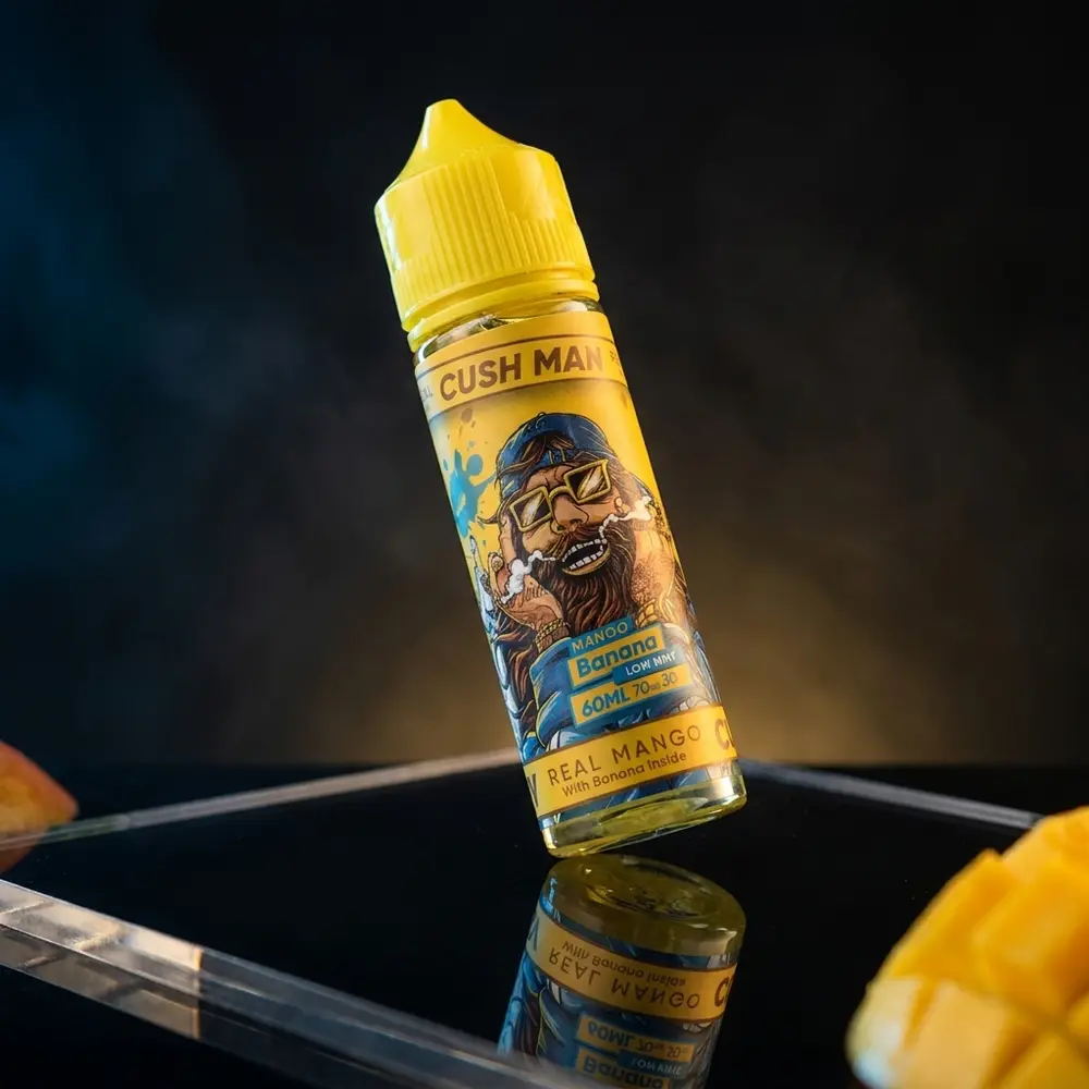 Frasco Nasty Juice Cush Man Mango Banana inclinado sobre acrilico preto com luzes quentes e reflexos - Vapor Gringo