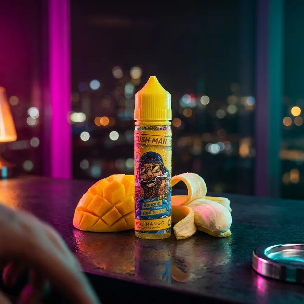 Frasco Nasty Juice Cush Man com fatias de manga num balcão neon urbano, luzes RGB e bokeh - Vapor Gringo