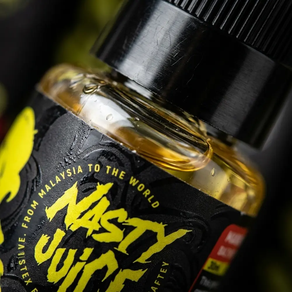 Close-up do rótulo do Líquido Nasty Juice Salt Mango Lassi, textura do vidro, gotas de condensação e reflexos metálicos - Vapor Gringo