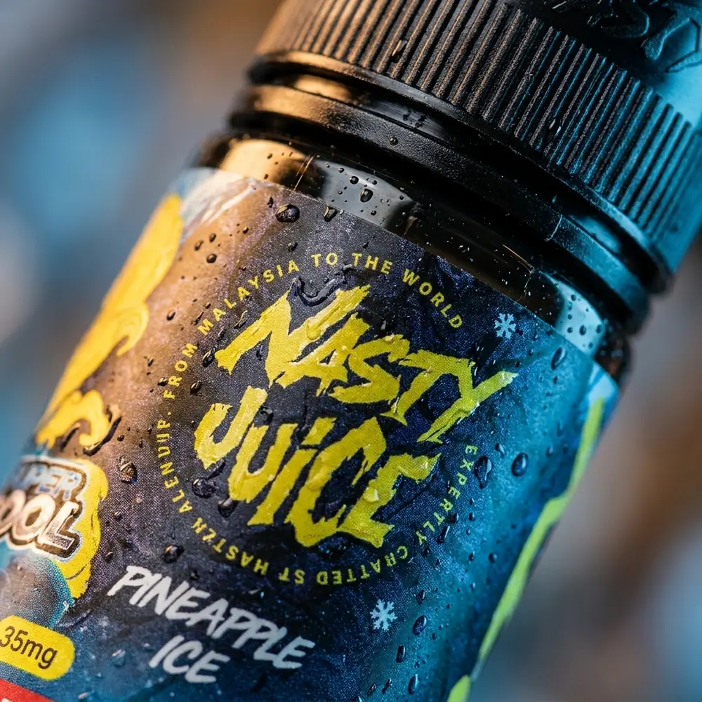 Close-up do rótulo e bico do frasco Nasty Juice Pineapple Ice com gotas de condensação e reflexos - Vapor Gringo