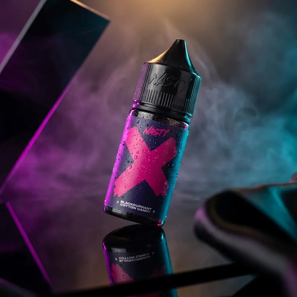 Garrafa de Liquido Nasty Juice Salt Blackcurrant Cotton Candy em estúdio escuro com reflexos roxos e gotas - Vapor Gringo
