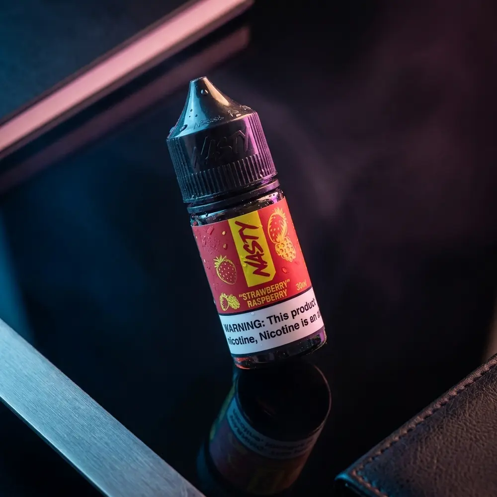 Garrafa Líquido Nasty Juice Salt Strawberry Raspberry sobre acrílico preto com luzes azul e magenta e gotas de condensação - Vapor Gringo