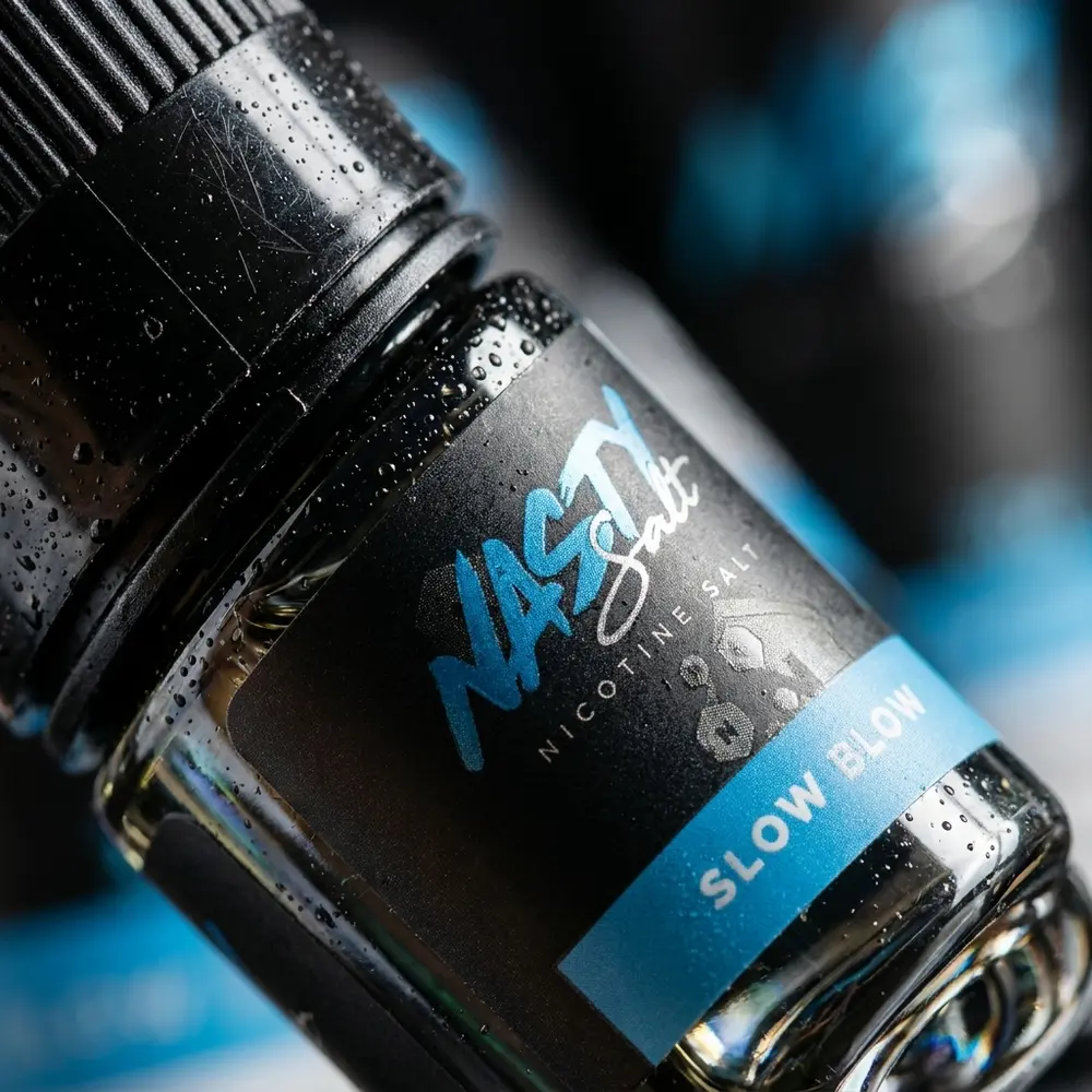 Detalhe do rótulo Nasty Juice Slow Blow com gotas de condensação e foco na tipografia e textura do material - Vapor Gringo