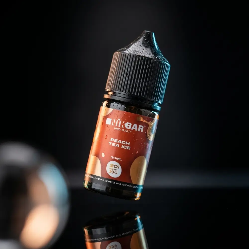 Garrafa do Nikbar Salt Peach Tea Ice inclinada sobre acrilico reflexivo com iluminacao pêssego e gelo - Vapor Gringo