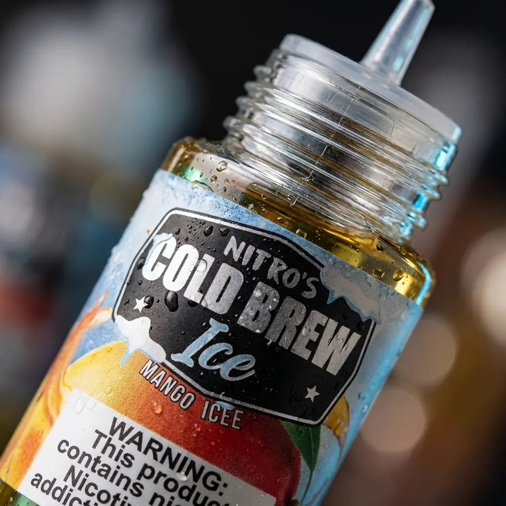 Detalhe macro do rótulo e bico da garrafa Líquido Nitro's Cold Brew Mango Ice com gotas de condensação - Vapor Gringo