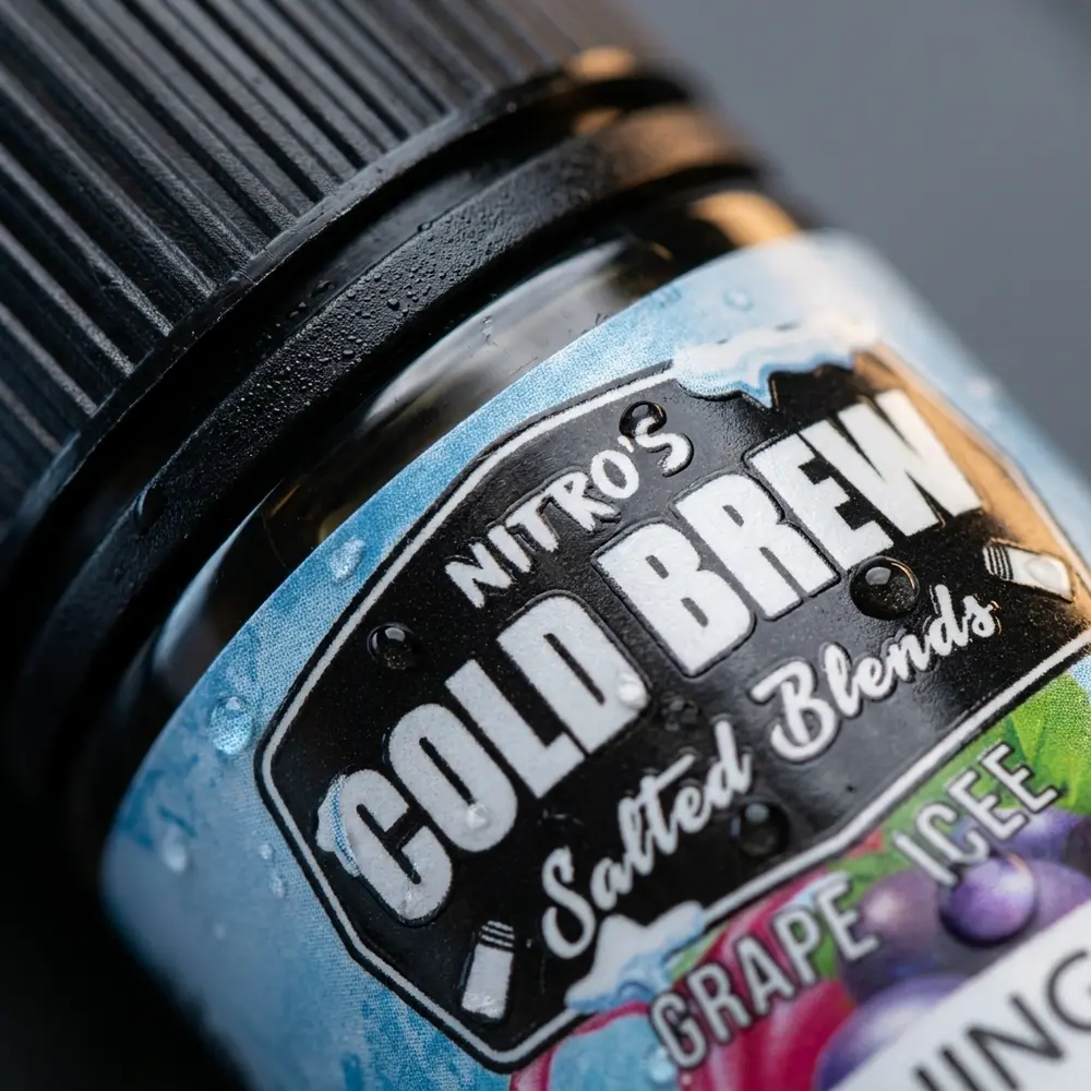Close-up do rotulo e bico do e-liquido Nitros Grape Ice com gotas de condensacao e reflexos metalizados - Vapor Gringo