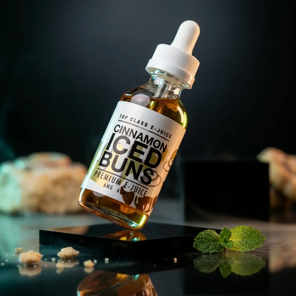 Frasco 60ml Liquido Top Class Cinnamon Iced Buns sobre acrilico preto, luzes mint e douradas e migalhas - Vapor Gringo