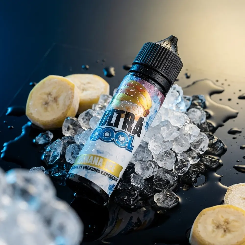 Líquido Ultra Cool Salt Banana Ice em close sobre base acrílica molhada com gelo, gotas e luzes azul e amarela - Vapor Gringo