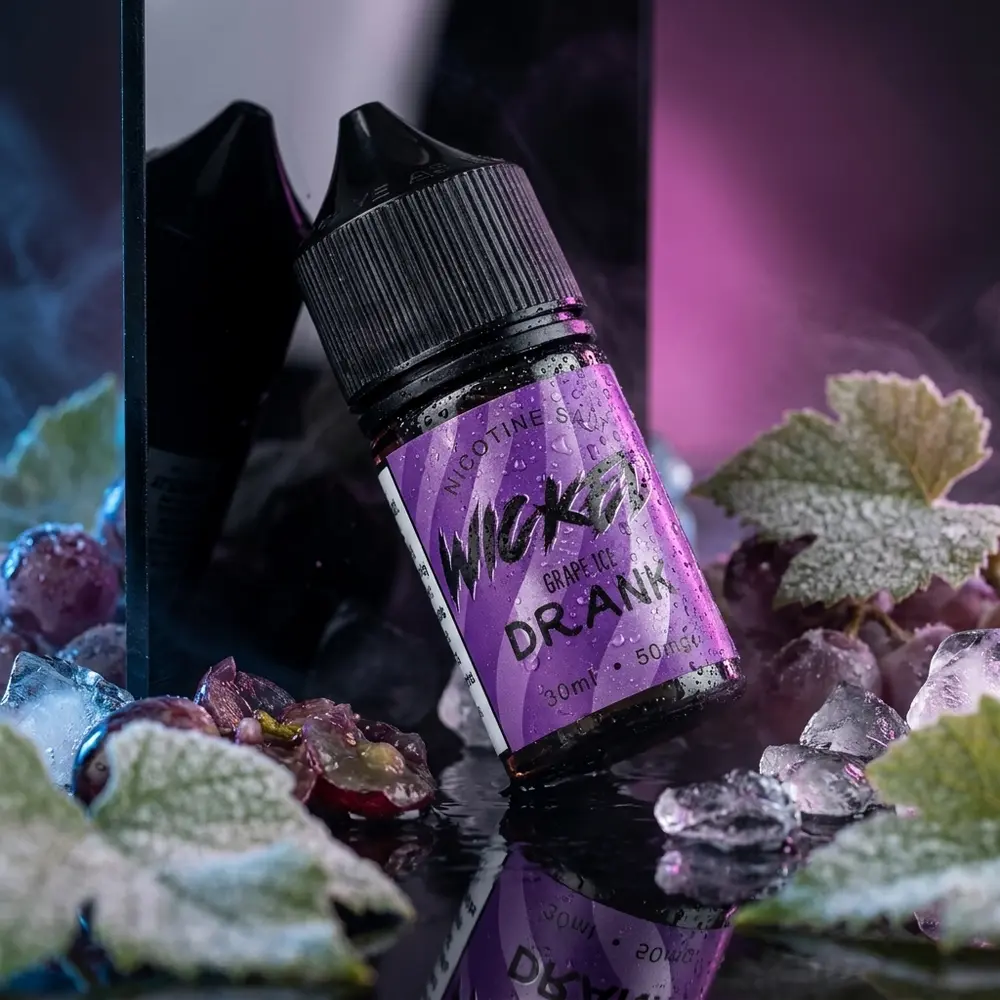 Garrafa do Líquido Wicked Salt Grape Ice sobre acrílico preto com condensação, uvas e gelo - Vapor Gringo