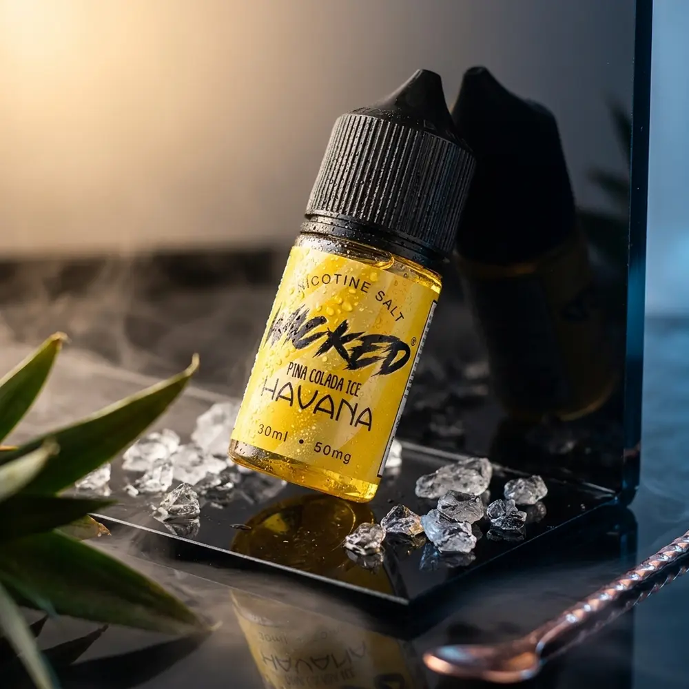 Garrafa de líquido Wicked Salt Pina Colada Ice Havana sobre base acrílica com gelo e luzes dramáticas - Vapor Gringo