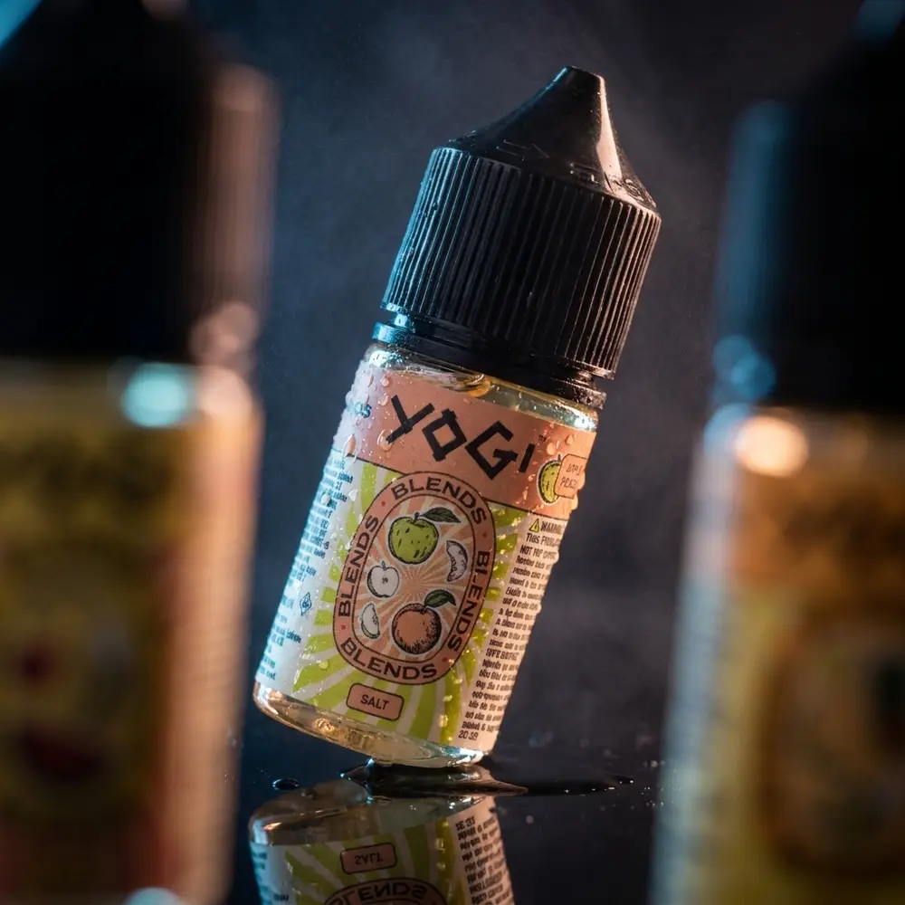 Garrafa Líquido Yogi Salt Ice apoiada em acrílico preto com condensação e luzes frias e quentes ao fundo - Vapor Gringo