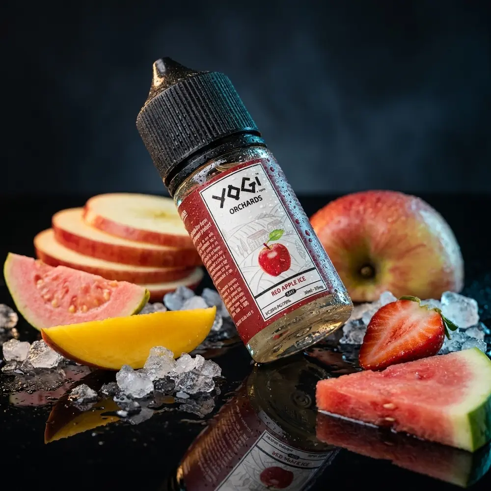 Garrafa Liquido Yogi Salt Ice Orchards Edition inclinada sobre acrilico preto com frutas, gelo e iluminacao azul-vermelha - Vapor Gringo