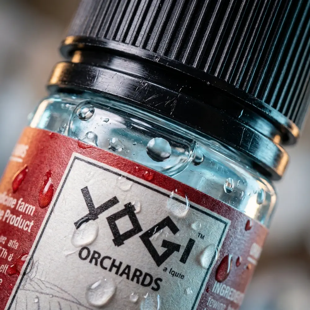 Plano macro da garrafa Liquido Yogi Salt Ice Orchards, foco na etiqueta, bico e gotas de condensacao no vidro - Vapor Gringo