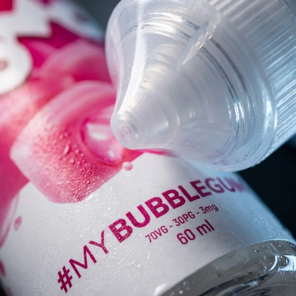 Close macro do rótulo do Líquido Zomo Bubblegum com gotas, textura do rótulo e bico do frasco em detalhe - Vapor Gringo