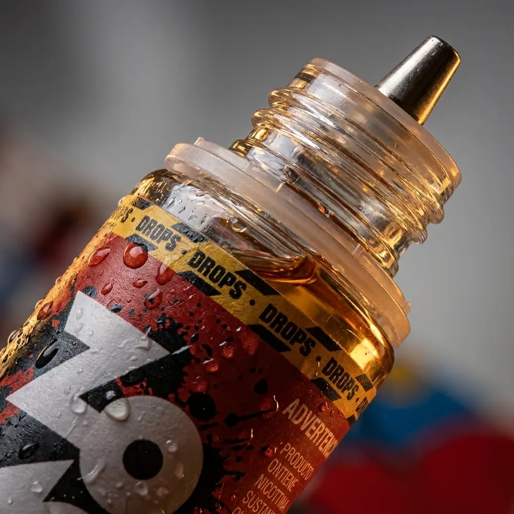 Close-up do bico e rótulo do Líquido Zomo Cherry Bomb Drops, gotas de condensação e textura do vidro em detalhe. - Vapor Gringo