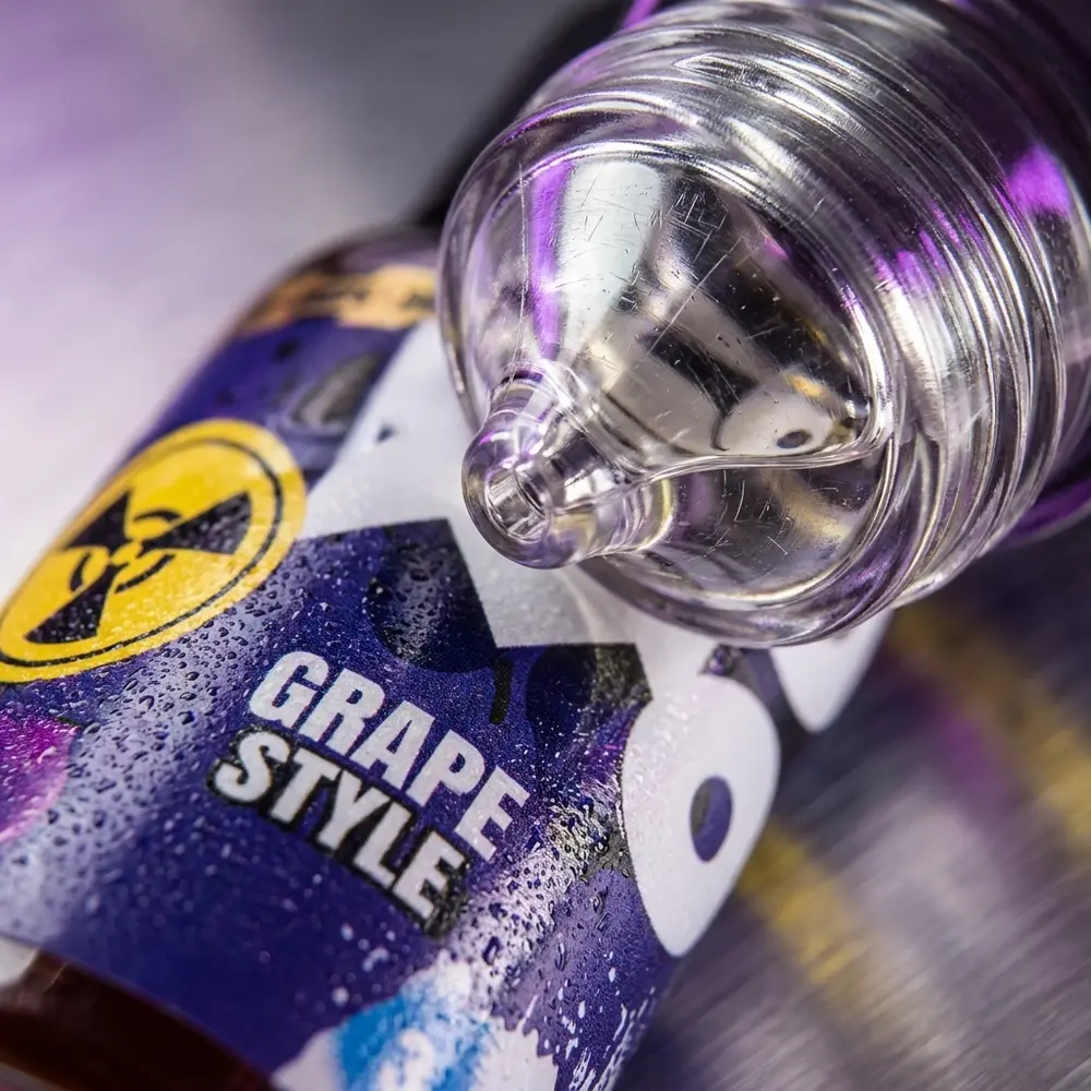 Detalhe do rótulo e bico do Líquido Zomo Grape Style Drops com gotas, textura e micro-reflexos - Vapor Gringo