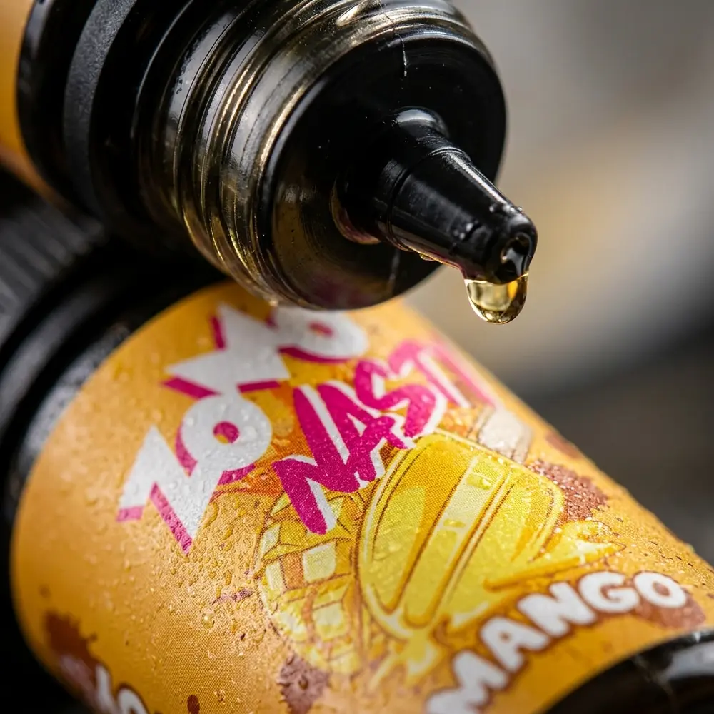 Detalhe macro do rotulo e bocal do liquido Zomo Nasty Salt Mango Picole com condensacao e gotas de liquido - Vapor Gringo