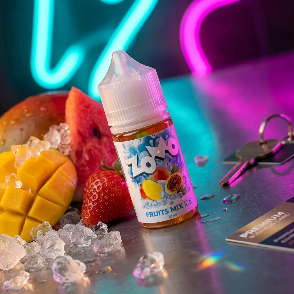 Frasco Zomo Salt Fruit Mix Ice sobre balcão metálico neon com frutas fatiadas e gelo ao redor. - Vapor Gringo