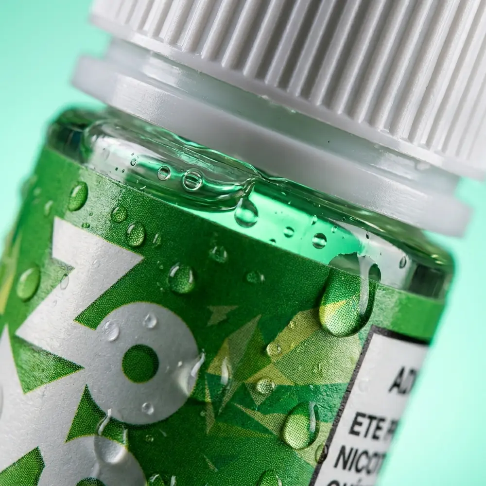 Close-up da etiqueta e bocal do Líquido Zomo Salt Pure Mint com gotas de condensação e reflexos metálicos - Vapor Gringo