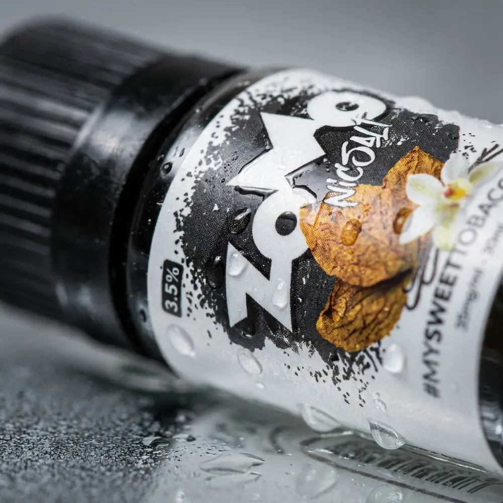 Macro do rótulo e bico da garrafa Zomo Salt Sweet Tobacco 30ml com gotas de condensação e reflexos nítidos - Vapor Gringo