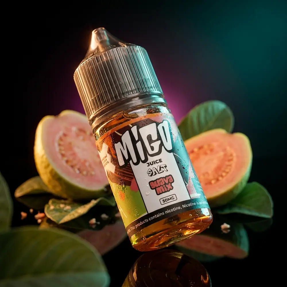 Garrafa Migo Salt Guava Mix inclinada sobre acrílico com goiabas frescas e iluminação âmbar/teal - Vapor Gringo