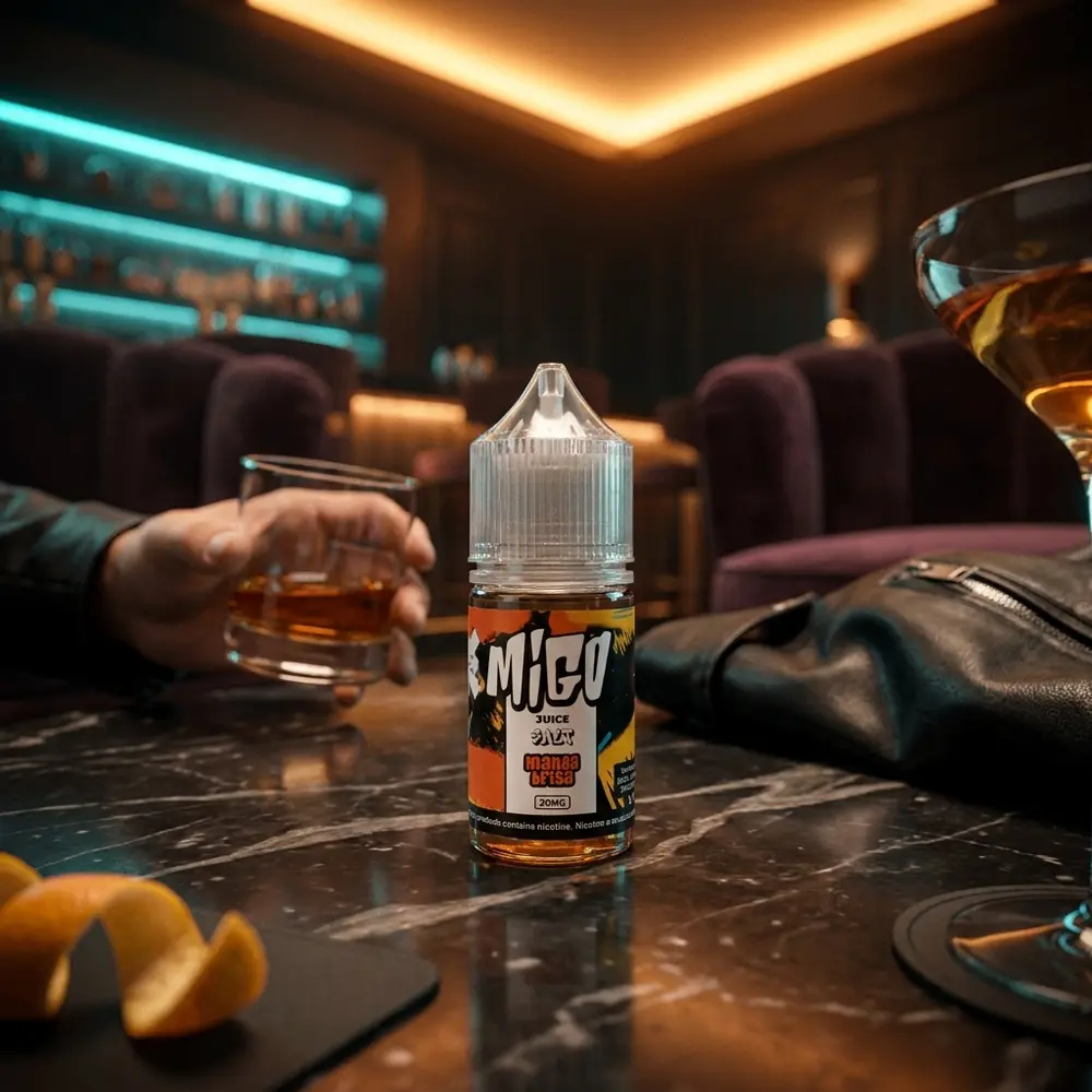 Frasco Migo Salt Mangabrisa 30ml sobre mesa de marmore em lounge luxuoso com copo e luz quente - Vapor Gringo