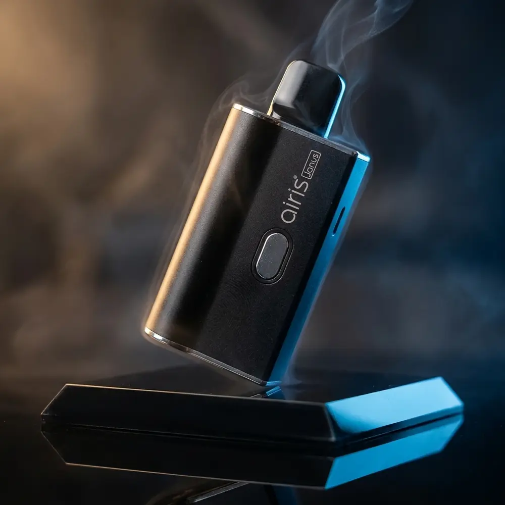 Mod AIRIS Janus 2in1 em close-up sobre base acrílica preta com iluminação dramática e reflexos metálicos - Vapor Gringo