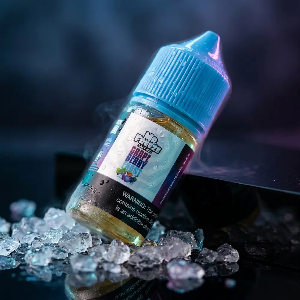 Garrafa Mr. Freeze Salt Grape Berry Frost inclinada sobre acrílico preto com gelo e luzes magenta e teal - Vapor Gringo