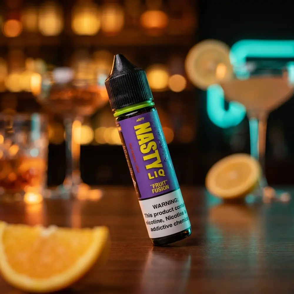 Frasco Nasty Juice Salt Fruit Fusion 30ml apoiado em mesa de lounge elegante, fatia de fruta e luzes de bar desfocadas - Vapor Gringo