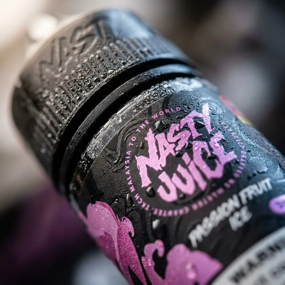 Close-up do rotulo e bocal da Nasty Juice Salt Passion Fruit Ice com gotas de condensacao e textura do papel - Vapor Gringo