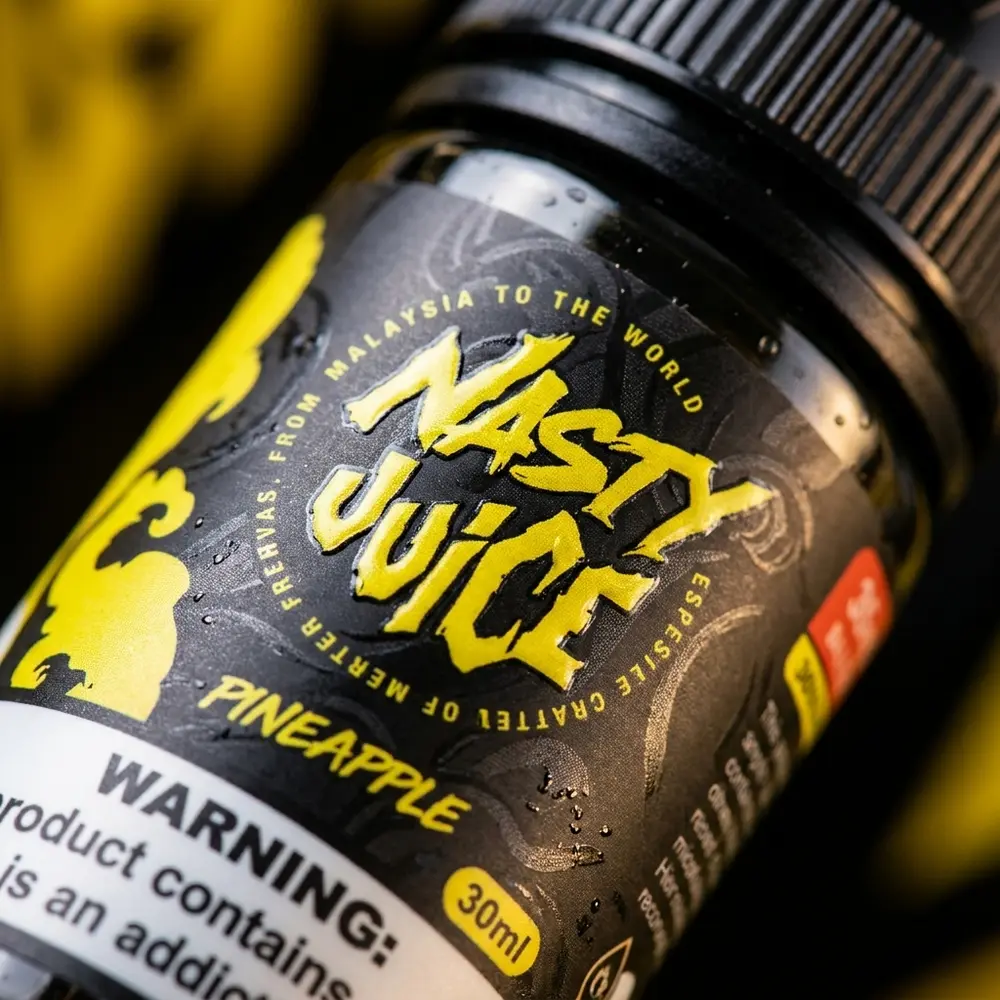 Macro do rótulo e bico do Líquido Nasty Juice Salt Pineapple com gotas de condensação e reflexos - Vapor Gringo