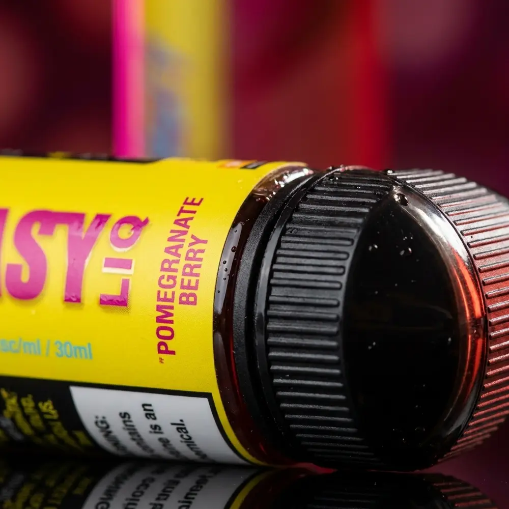Detalhe macro do rótulo Nasty Juice Salt Pomegranate Berry com vidro, bico e gotas de condensacao e reflexos vermelhos - Vapor Gringo
