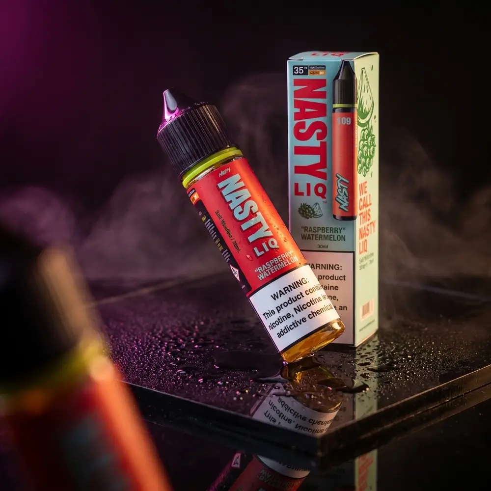Garrafa Nasty Juice Salt Raspberry Watermelon sobre acrílico preto com condensação e luzes rosa-âmbar - Vapor Gringo