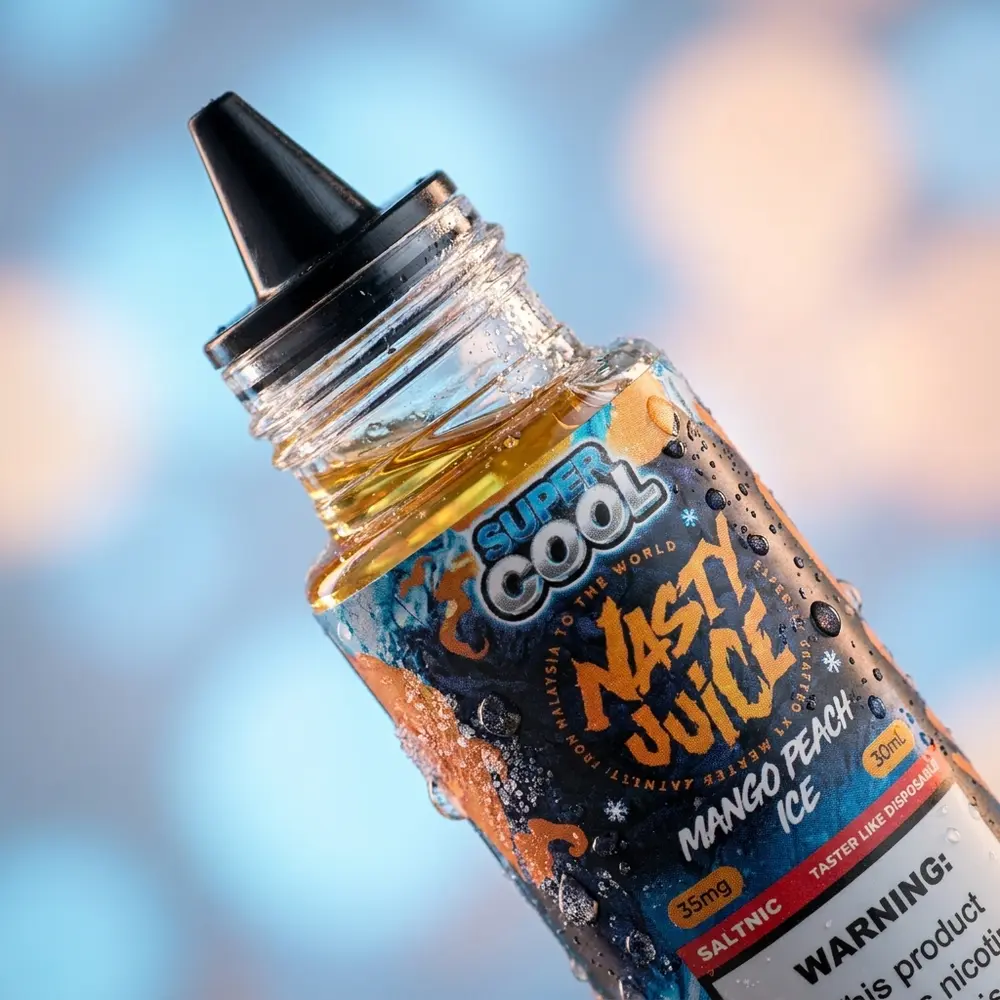 Close-up do rótulo e bico do frasco Nasty Juice Salt Super Cool Mango Peach Ice com gotas de condensação e micro-reflexos - Vapor Gringo
