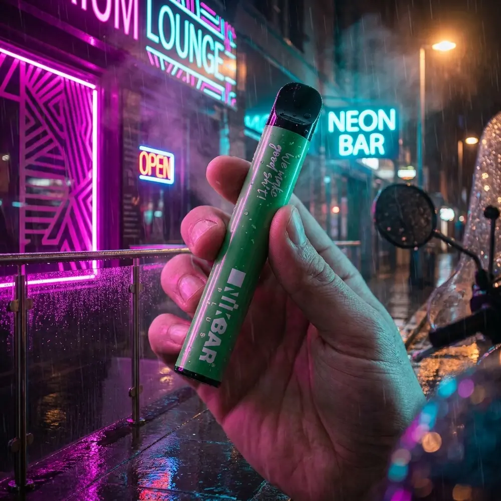 Pod descartavel NikBar Plus Cool Mint segurado por mao na noite urbana com neon e reflexos molhados - Vapor Gringo
