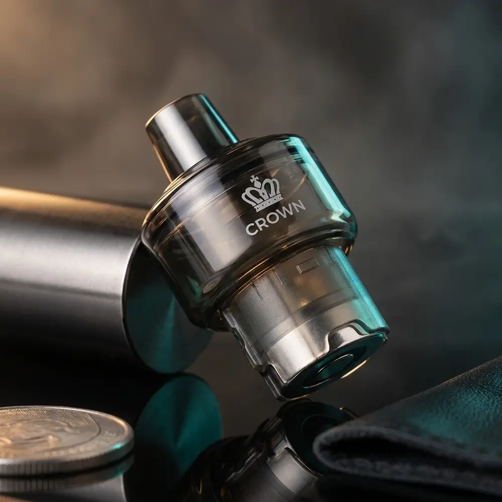 Pod de Reposicao Crown M Uwell inclinado sobre acrilico preto com luzes teal e magenta e reflexos metalicos - Vapor Gringo