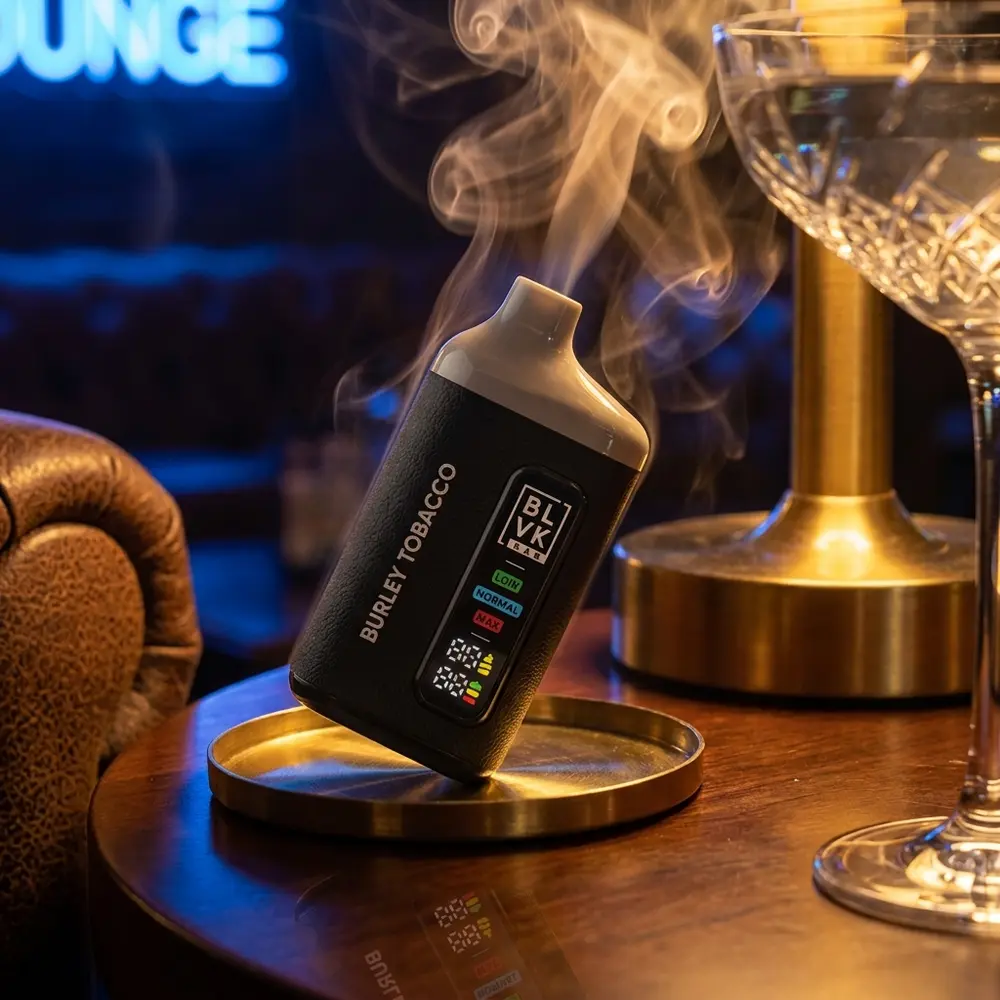 Pod descartavel BLVK Bar Burley Tobacco apoiado em porta-copos metalico numa lounge sofisticada com luz quente - Vapor Gringo