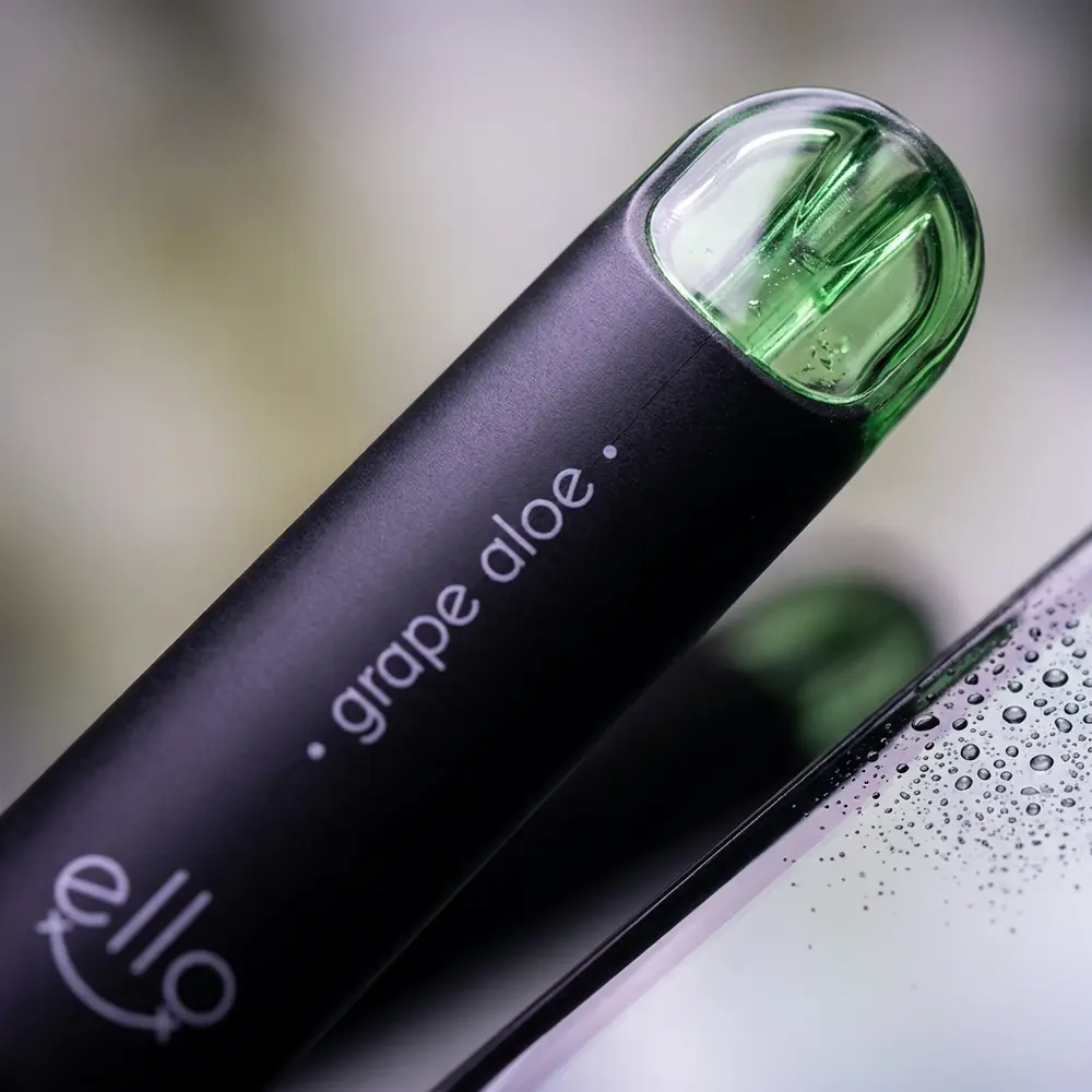 Close-up macro do bocal e do rótulo do Pod Blvk Ello Grape Aloe mostrando textura, logo e reflexos - Vapor Gringo