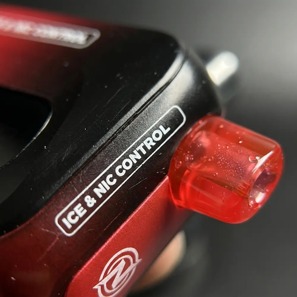 Macro do logo e bocal do Pod BLVK Just Juice com gotas de condensacao e textura metalica detalhada - Vapor Gringo