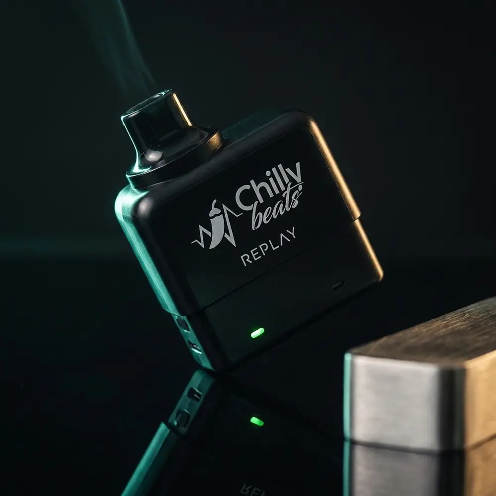 Pod Descartável Chilly Beats Replay sobre base acrílica reflexiva em estúdio, LED aceso e iluminação dramática - Vapor Gringo