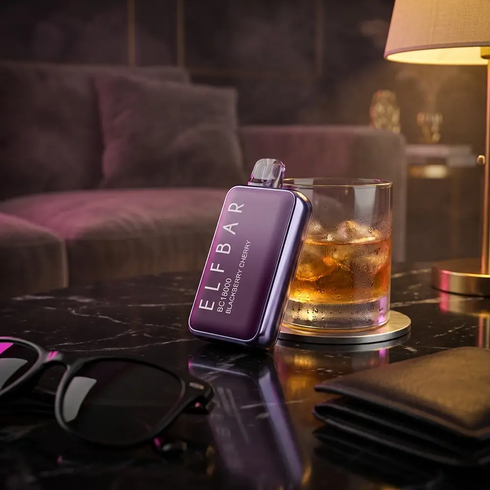 Pod Descartavel Elf Bar BC18000 Blackberry Cherry apoiado em mesa de marmore num lounge, copo borrado e luzes quentes ao fundo - Vapor Gringo
