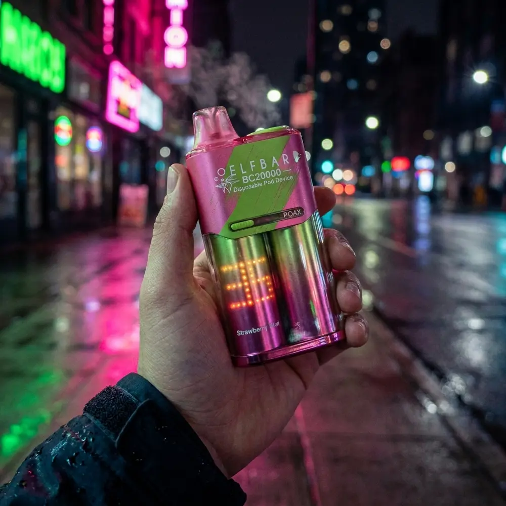 Pod descartavel Elf Bar BC20000 Strawberry Kiwi na mao de um vaper em rua noturna com reflexos neon rosa e verde - Vapor Gringo