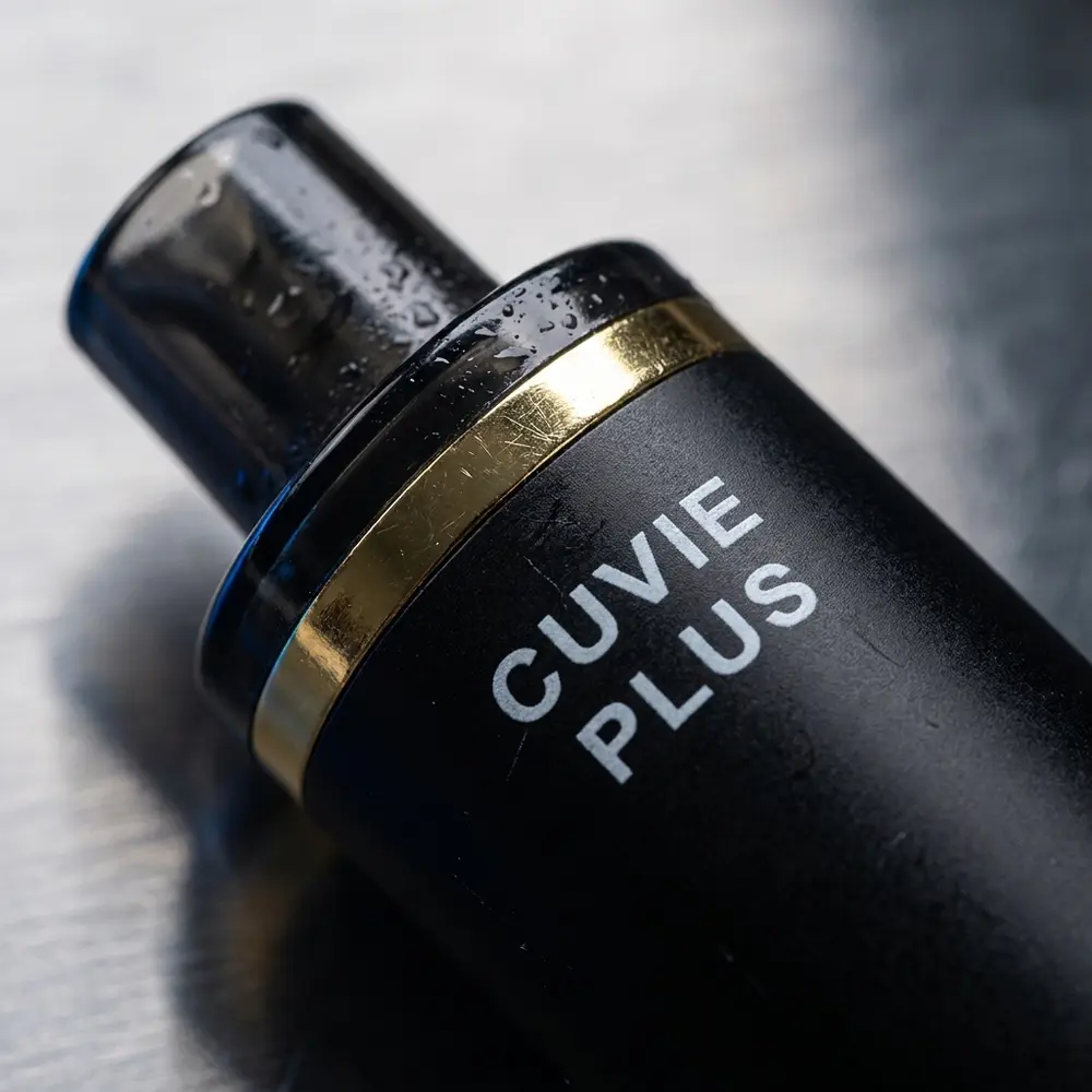 Close-up do bocal e logotipo do HQD Cuvie Plus com condensacao e reflexos metalicos - Vapor Gringo