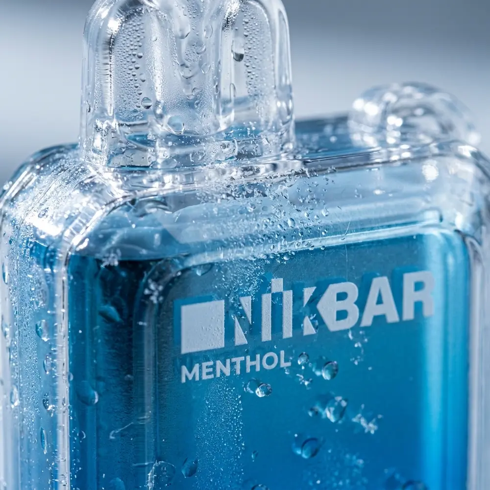 Detalhe do Pod Descartavel NikBar Menthol mostrando boca, rótulo e gotas de gelo com textura metálica - Vapor Gringo