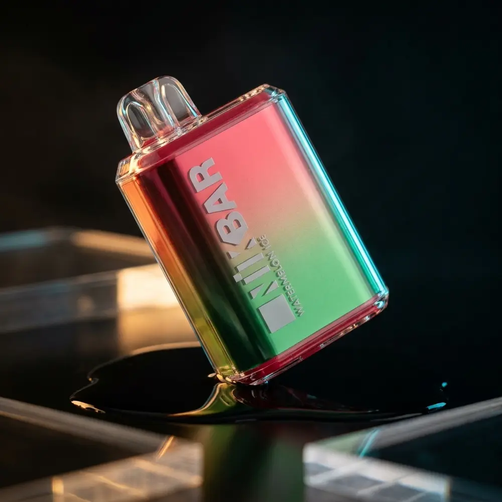 Pod Descartavel NikBar Watermelon Ice pousado em superficie preta refletiva, iluminacao ciano-ambar e nevoa sutil - Vapor Gringo