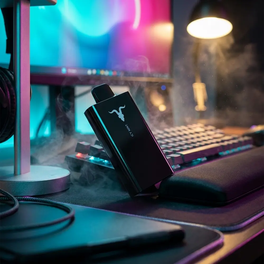 Pod Descartável V80 Ignite Black apoiado em mesa gamer RGB, luzes cyan-magenta e acessórios desfocados - Vapor Gringo