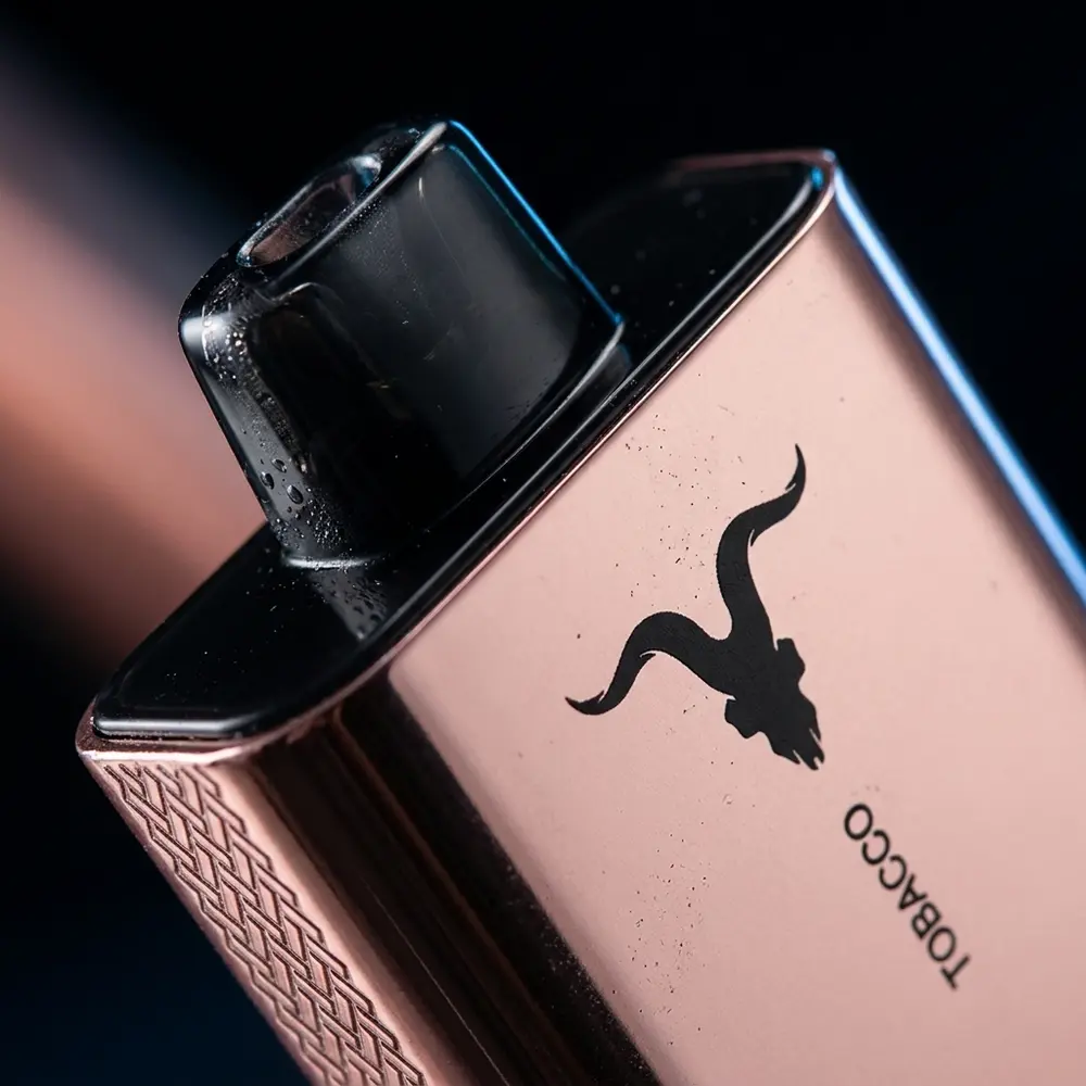 Close-up do bocal e do logo do Pod V80 Ignite Rose Gold com gotas de condensação e reflexos metálicos - Vapor Gringo
